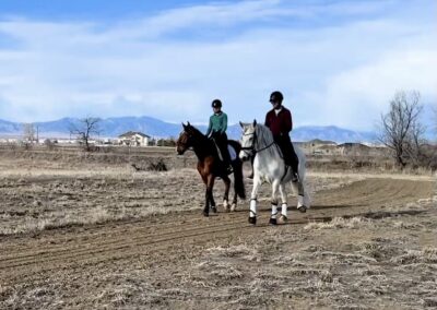Two people horseback riding on a trail.