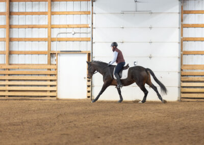 Person riding a horse inside an indoor arena.