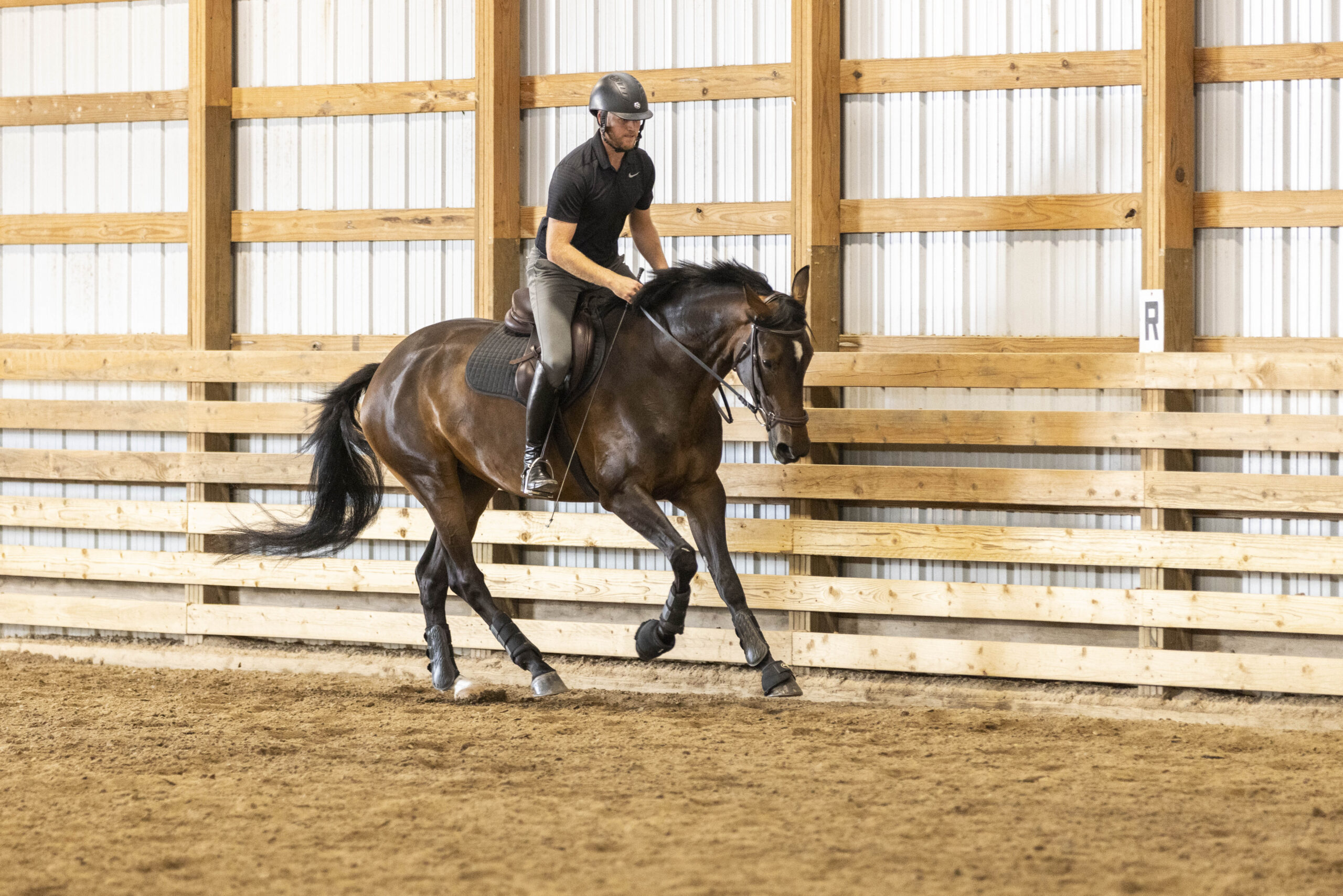 Woman riding a horse inside an indoor arena.
