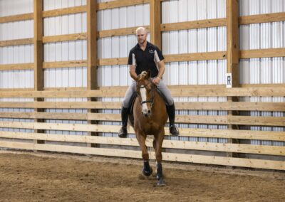 A person riding a horse inside an indoor arena.